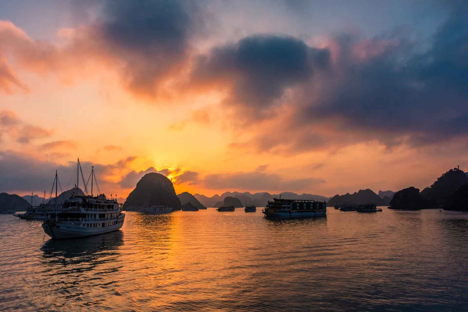 Cruise junks among the limestone islands of Ha Long Bay at a fiery sunset, Vietnam