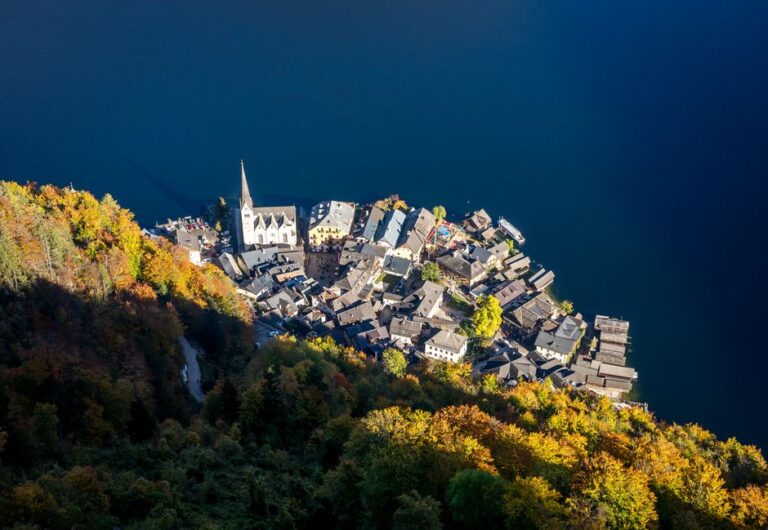 Aerial photograph of picturesque Hallstatt, Austria, with colorful autumn foliage and a tranquil lake.