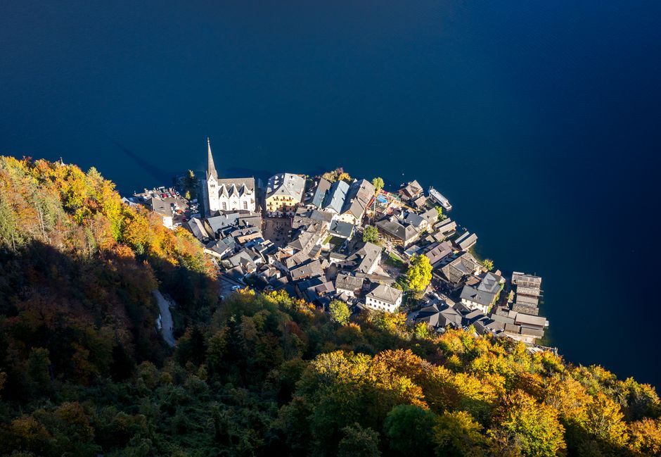 Aerial photograph of picturesque Hallstatt, Austria, with colorful autumn foliage and a tranquil lake.