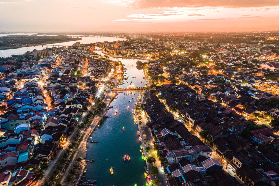Stunning aerial view of Hội An, Vietnam at sunset. City lights illuminate the historic riverside town.
