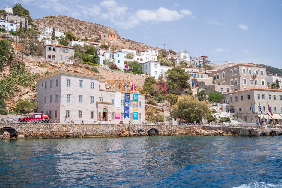 Picturesque view of Hydra's hillside architecture by the serene Mediterranean harbor.