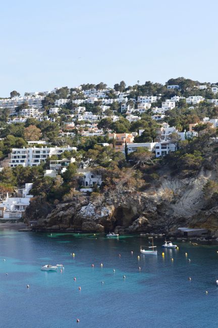 Stunning coastal landscape of Ibiza with boats in a tranquil bay under clear blue skies.