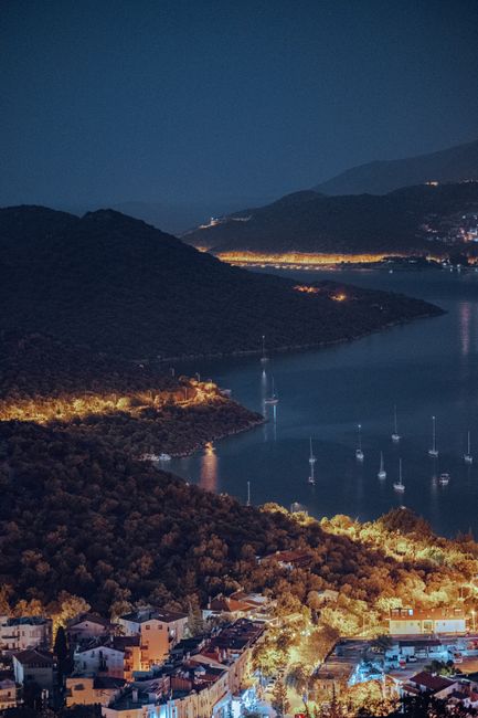 A stunning night aerial view of Kas, Turkey, showcasing the illuminated coastline and tranquil harbor.
