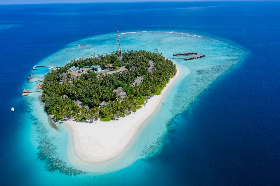 Stunning aerial shot of a tropical island resort in the Maldives, surrounded by turquoise waters and sandy beaches.