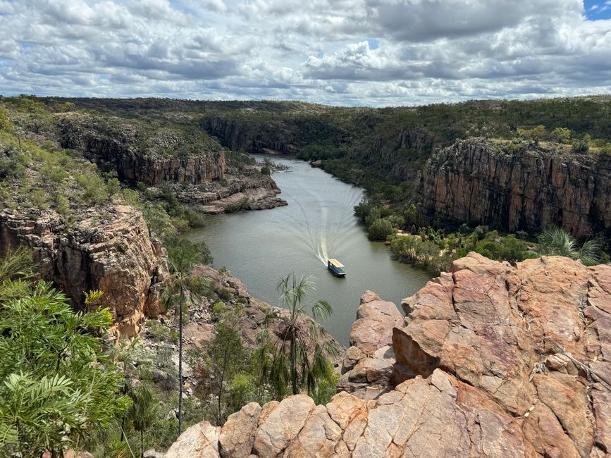 Aerial view of a boat navigating through a scenic gorge river surrounded by cliffs and forest.