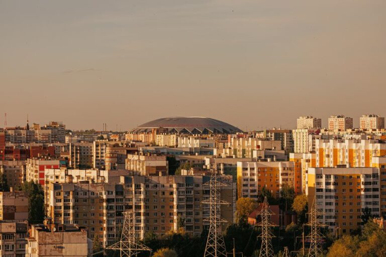 Aerial view of a cityscape with a large stadium and residential area at sunset.