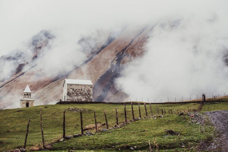 Church amidst foggy mountains in Stepanstminda, Georgia showcasing serene nature.