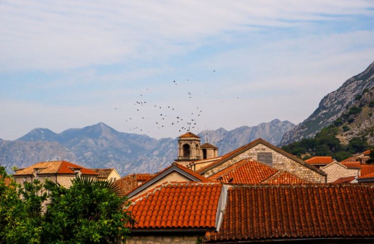 Picturesque view of a European town with red rooftops and stunning mountain backdrop, perfect for travel inspiration.