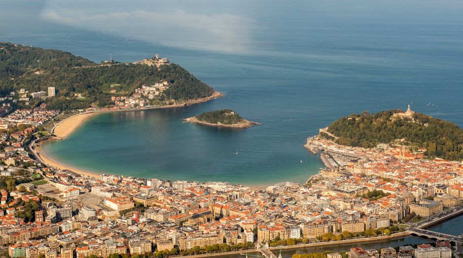 A stunning aerial view of La Concha Bay, San Sebastián, with lush hills and cityscape.