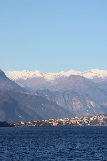 Breathtaking lake Como with snow-capped Alps in the background under clear blue skies.