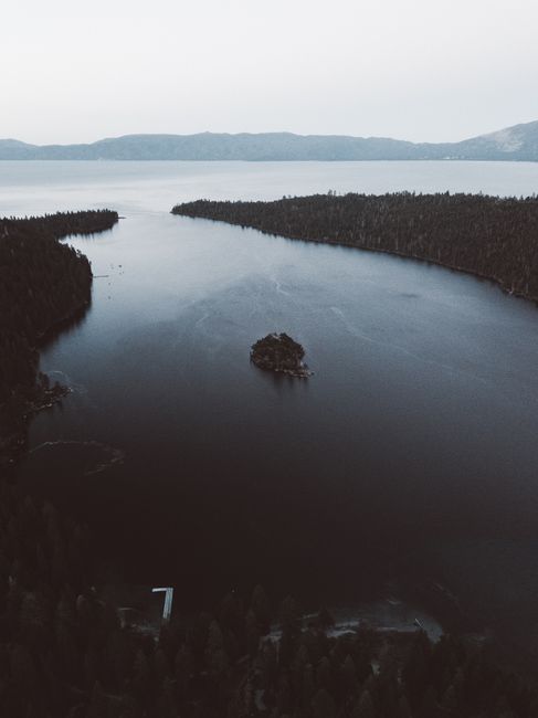 Serene aerial view of Lake Tahoe surrounded by forest at twilight, showcasing nature's beauty.