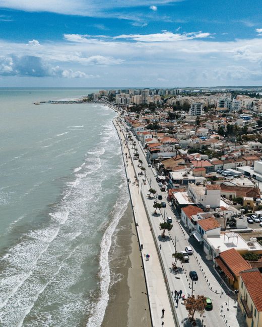 A stunning aerial shot of Larnaca's coastline showcasing buildings, beach, and waves.