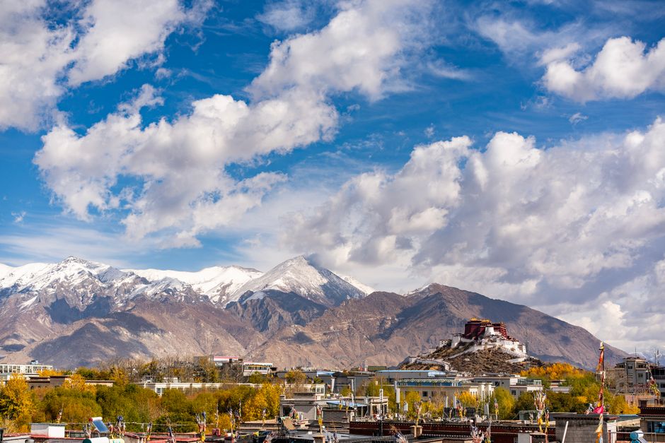 Breathtaking view of Potala Palace amidst mountains and vibrant autumn landscape in Lhasa, Tibet.