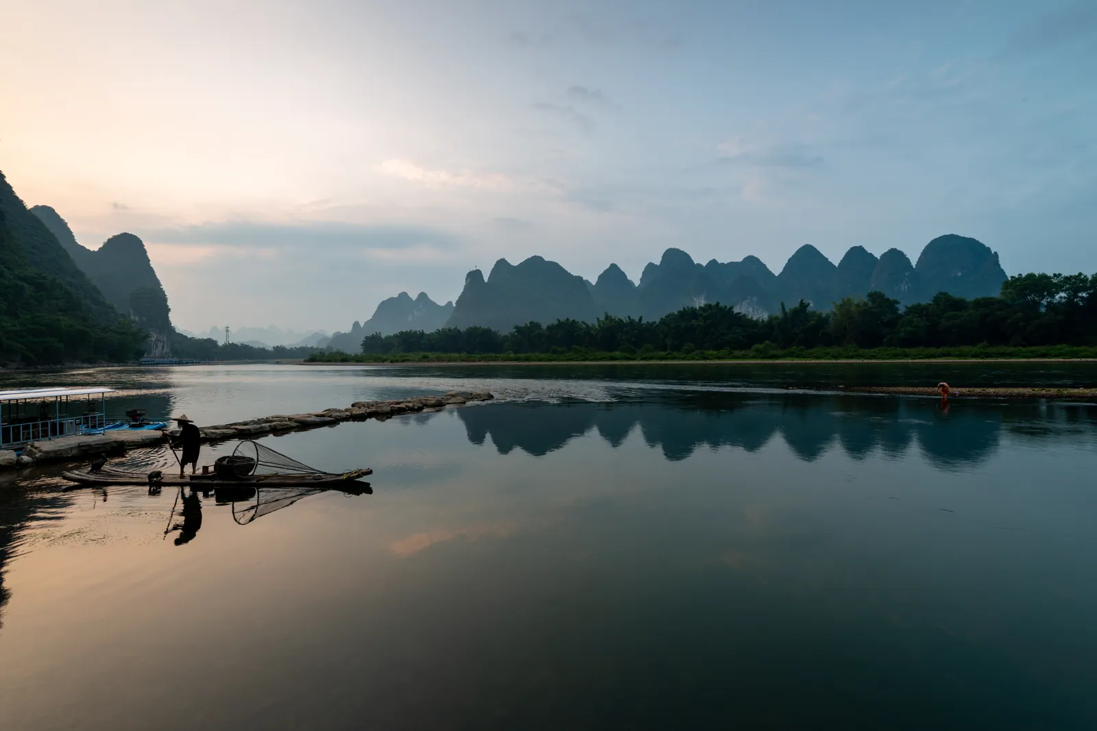 A fisherman on a bamboo raft on the Li River among karst peaks near Guilin, China