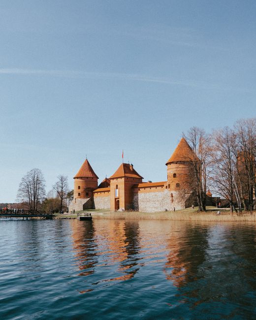 Historic Trakai Island Castle reflecting in Lake Galve on a clear day in Lithuania.
