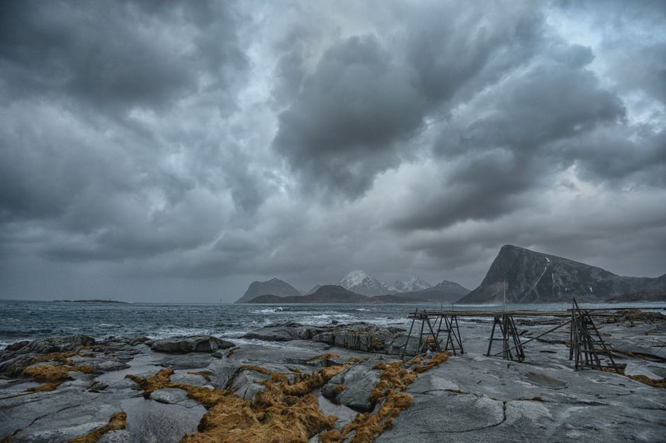Stormy clouds over the rugged Nordland coastline create a dramatic seascape with mountains in the distance.