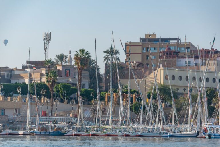 Sailboats moored in Luxor's marina against historic architecture.
