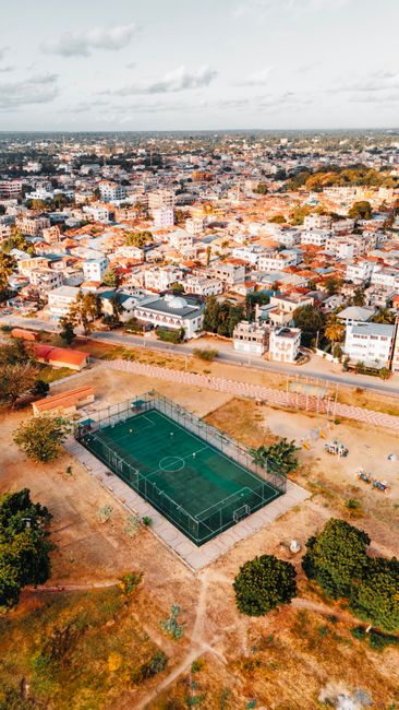 A vibrant aerial shot capturing the bustling urban landscape of Malindi with a central sports field.