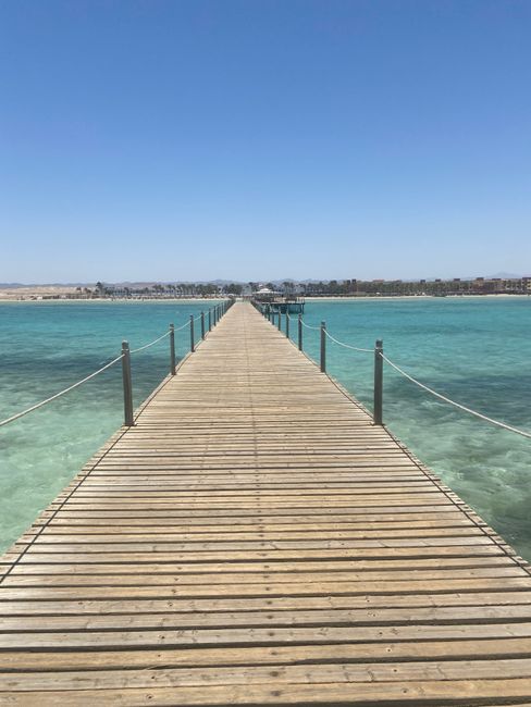 A long wooden pier stretches over clear turquoise waters in Marsa Alam, Egypt.