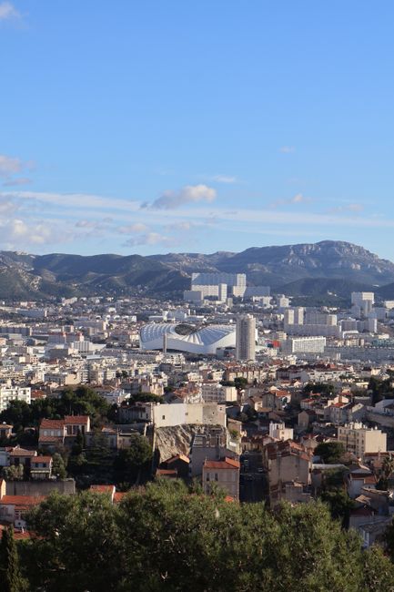Explore a panoramic view of Marseille, France, with distant mountains under a bright summer sky.