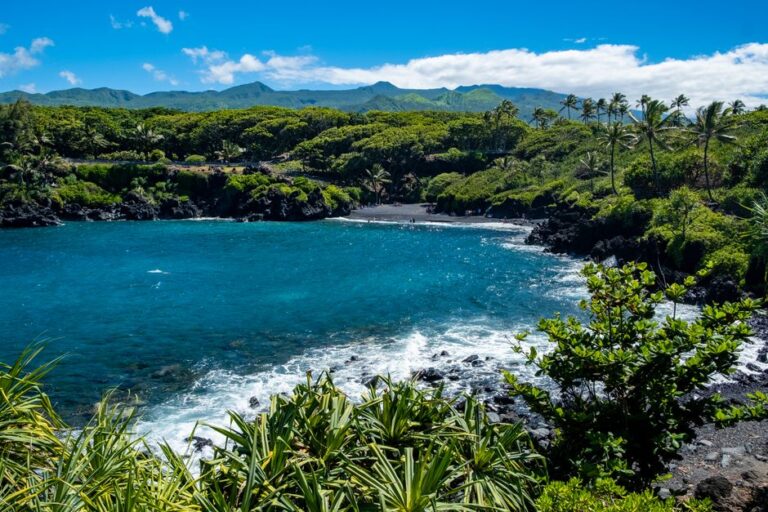 Explore the lush green landscapes and blue waters of Hana Bay, with its unique black sand beach and tropical flora.