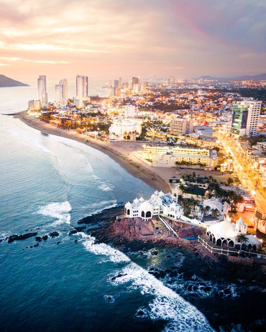 Stunning aerial view of Mazatlán's illuminated coastline at sunset with vibrant cityscape and coastal beauty.