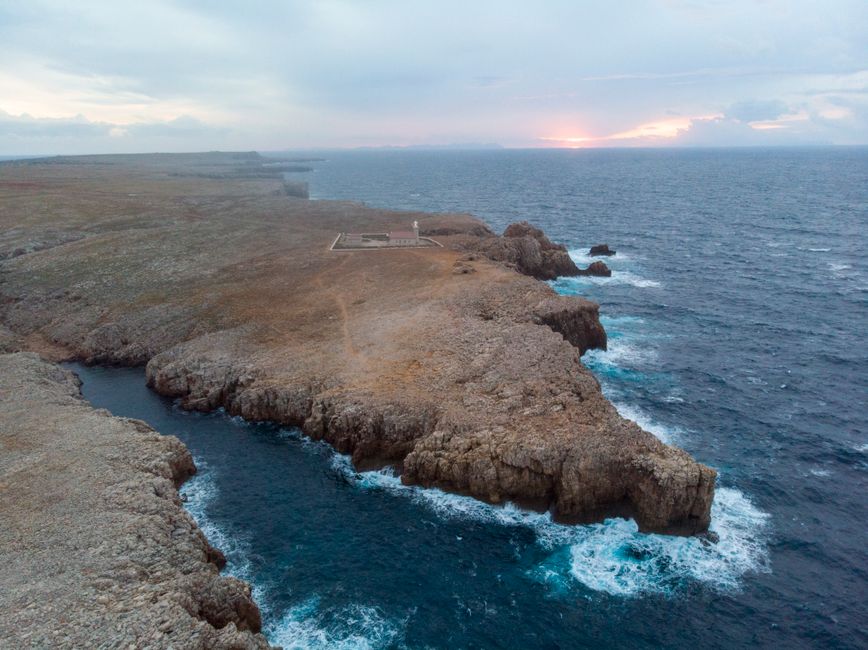 A breathtaking aerial shot of the rugged coastline of Ciudadela de Menorca during sunset, showcasing natural beauty.