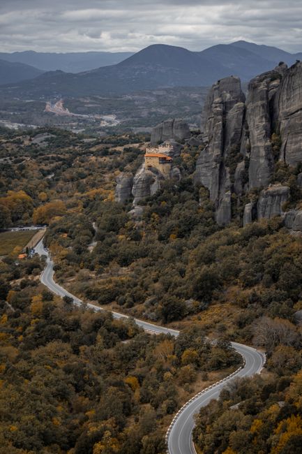 A breathtaking aerial view of the Meteora monasteries perched on rocky cliffs amidst autumn foliage.