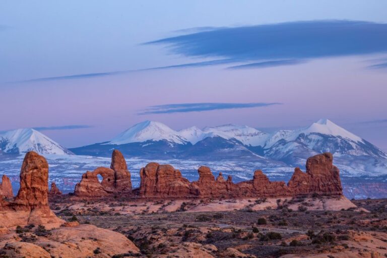 Stunning view of Arches National Park at dusk with snowcapped mountains in Utah.