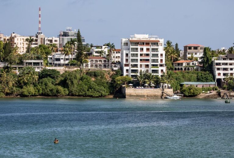 A picturesque view of Mombasa's waterfront featuring buildings and lush greenery.