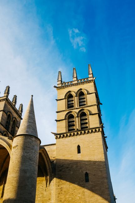 Low angle view of the Gothic cathedral towers in Montpellier, France against a clear blue sky.