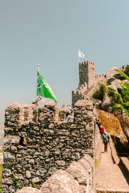 Tourists explore the ancient stone walls of a medieval castle in Sintra, Lisbon, Portugal.