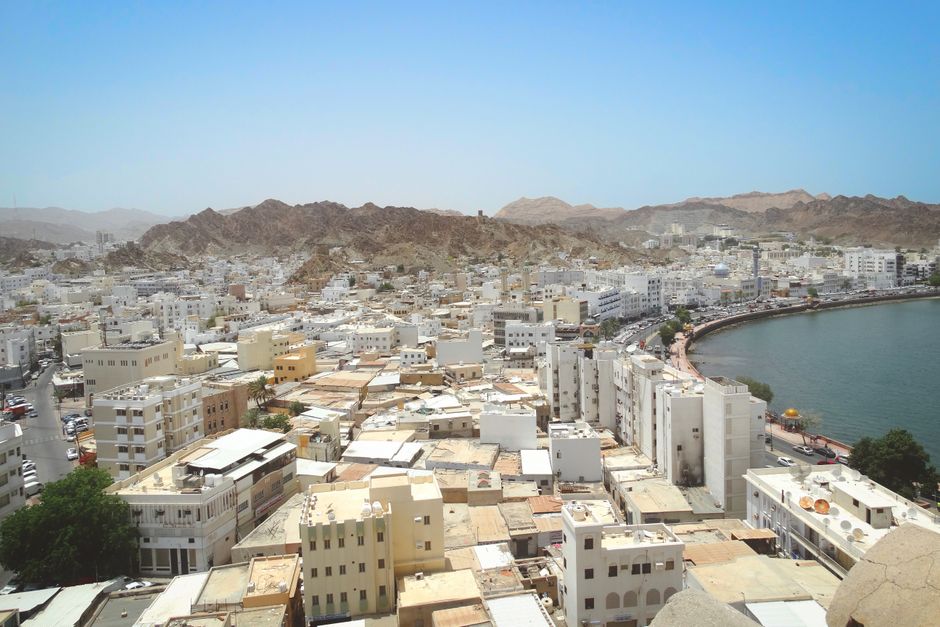 Aerial shot of Muscat's skyline with coastal view and mountains. Ideal for travel and geography content.