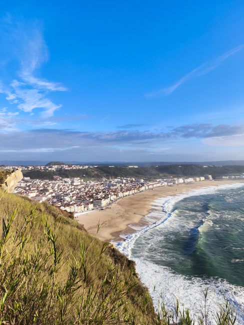 A beautiful coastal town with a sandy beach and ocean waves under a clear blue sky.