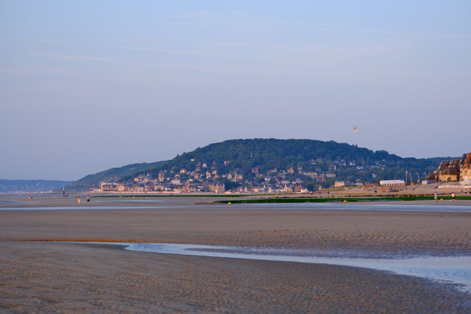 A picturesque view of Cabourg beach, Normandy, with hills in the background at dusk.