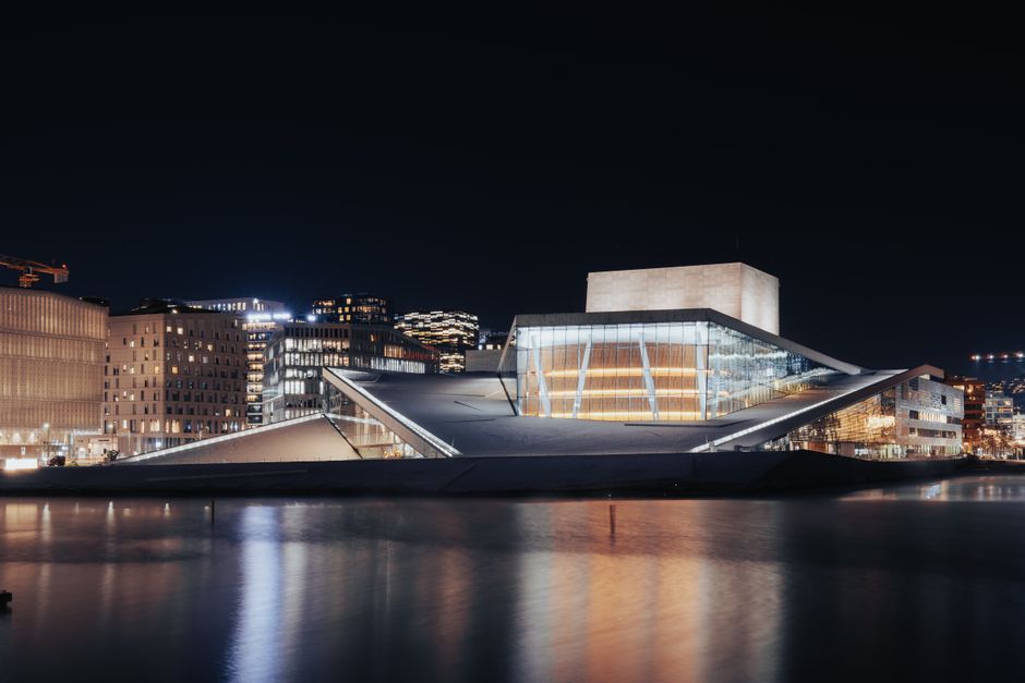 Stunning view of Oslo Opera House illuminated at night with city reflections.