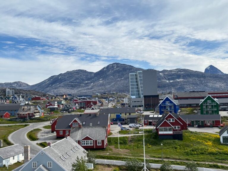 A picturesque view of Nuuk with colorful buildings against a mountainous backdrop.