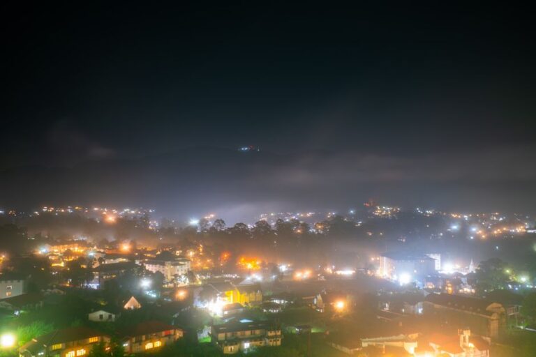 Captivating nighttime view of Nuwara Eliya, Sri Lanka, showcasing vibrant town lights under a misty sky.