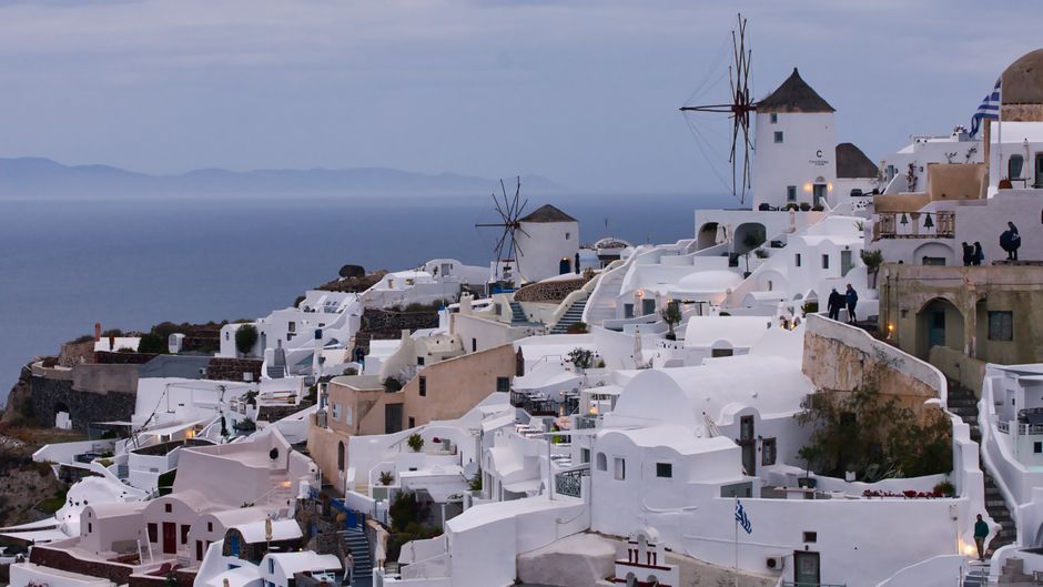 Beautiful view of Oia in Santorini, Greece, with white buildings and traditional windmills at dusk.