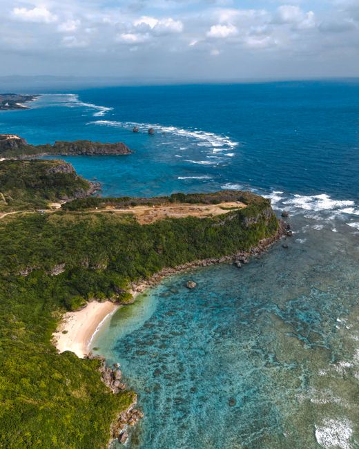Breathtaking aerial view of Okinawa's pristine coastline featuring lush greenery and turquoise waters.