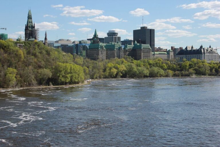 A scenic view of Ottawa's Parliament buildings and the Ottawa River on a clear day.