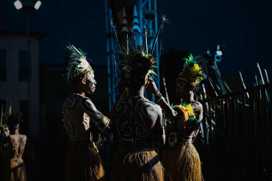 Dancers in traditional Papuan attire performing under night lights in Jayapura, Indonesia.