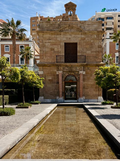 Charming historic chapel in Málaga, Spain with a tranquil reflecting pool.
