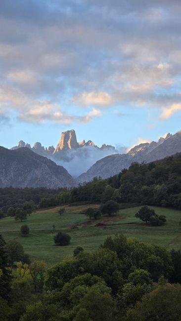 Captivating view of rugged mountain peaks under a cloudy sky with lush green valley.