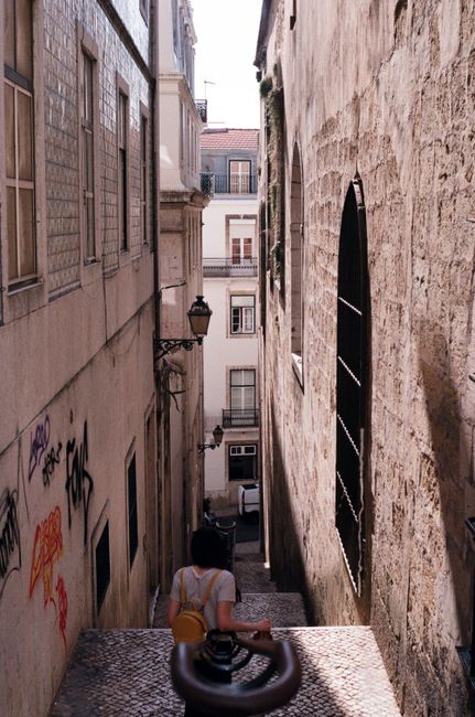 Explore the narrow alleyways of Lisbon with a person enjoying the scenic walk amidst historical architecture.