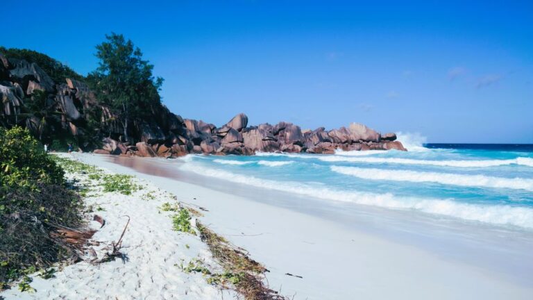 Pristine tropical beach with azure waves crashing against rocky coastline.
