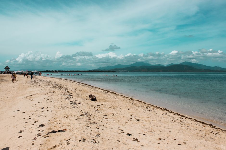 A tranquil beach scene in Puerto Princesa, Philippines with clear water and cloudy skies.