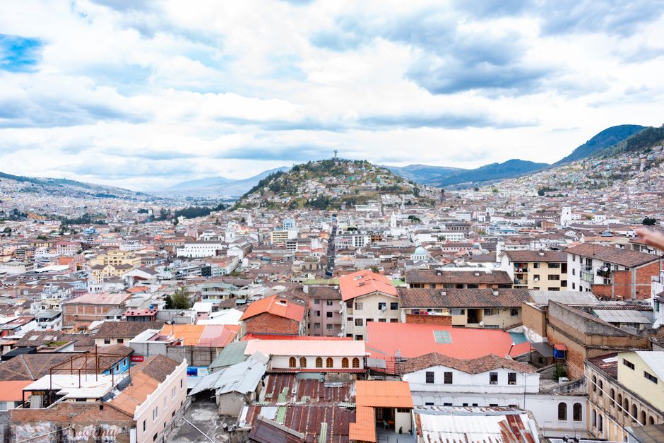 Aerial view showcasing Quito's urban landscape with rolling hills and colorful rooftops.
