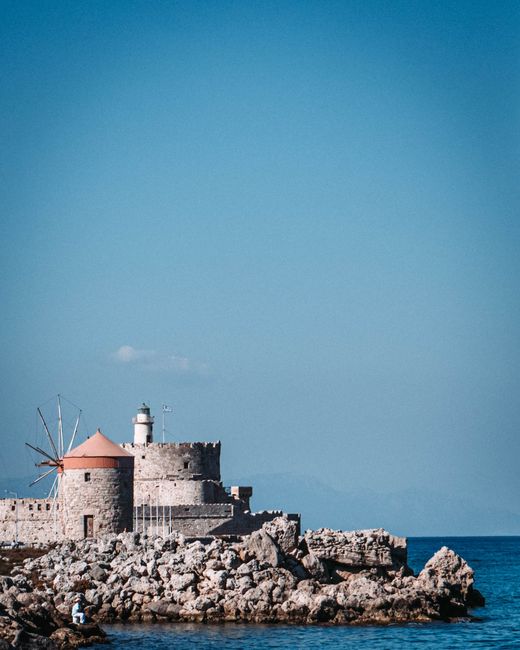 Explore the historic St. Nicholas Fortress and Lighthouse overlooking the Aegean Sea in Rhodes, Greece.