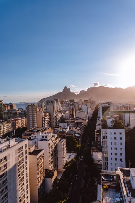 A breathtaking aerial view of Rio de Janeiro's cityscape with mountains and blue sky at sunset.